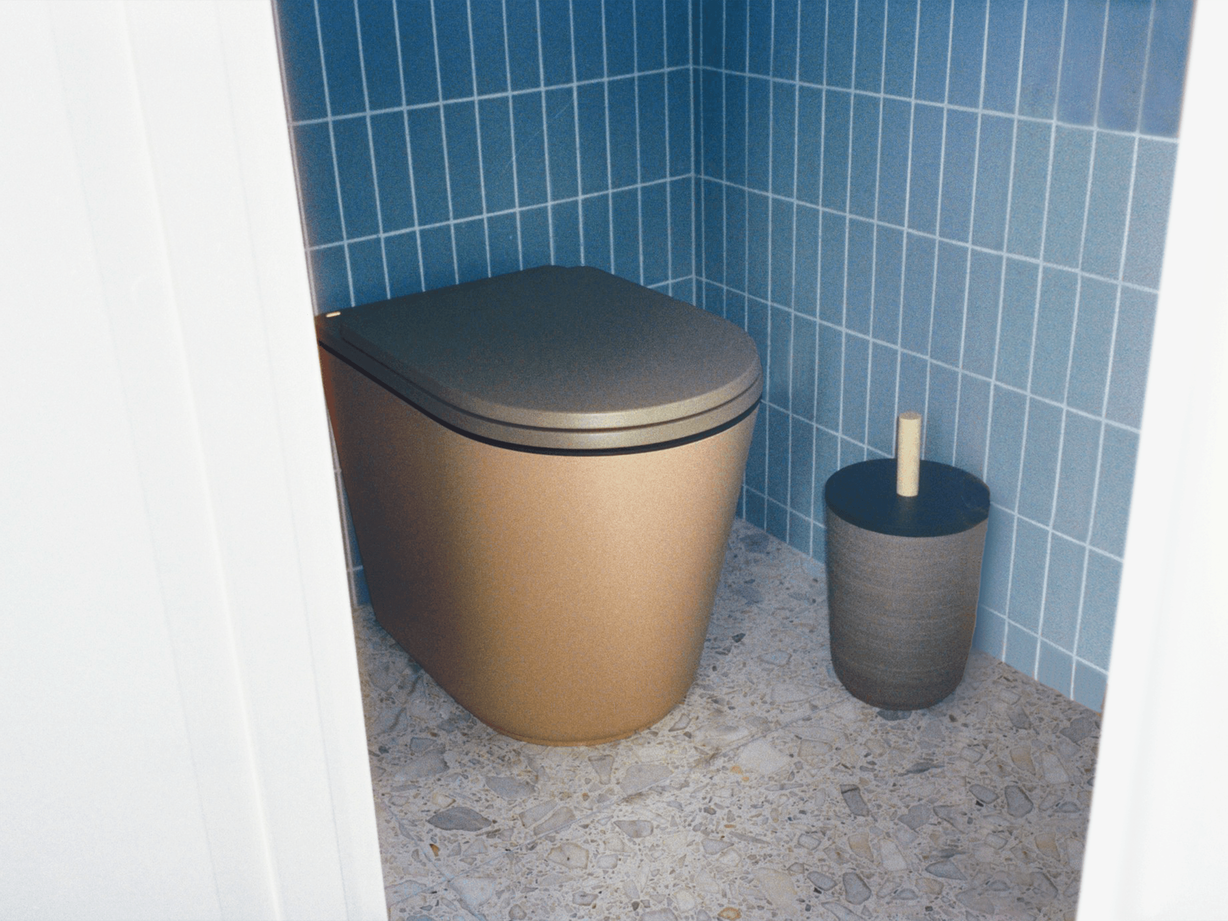 Beige komposttoalett med mörkgrönt lock i badrum med blå kakel och terrazzo